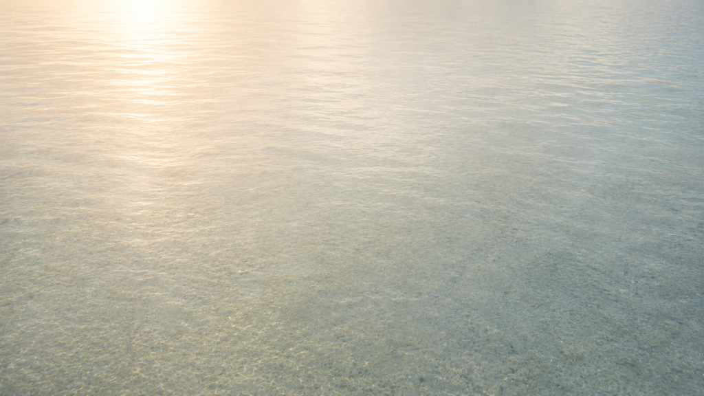 A soft, minimalist image of still shallow water with gentle light reflections and quiet neutral tones creating a calm and spacious feeling.